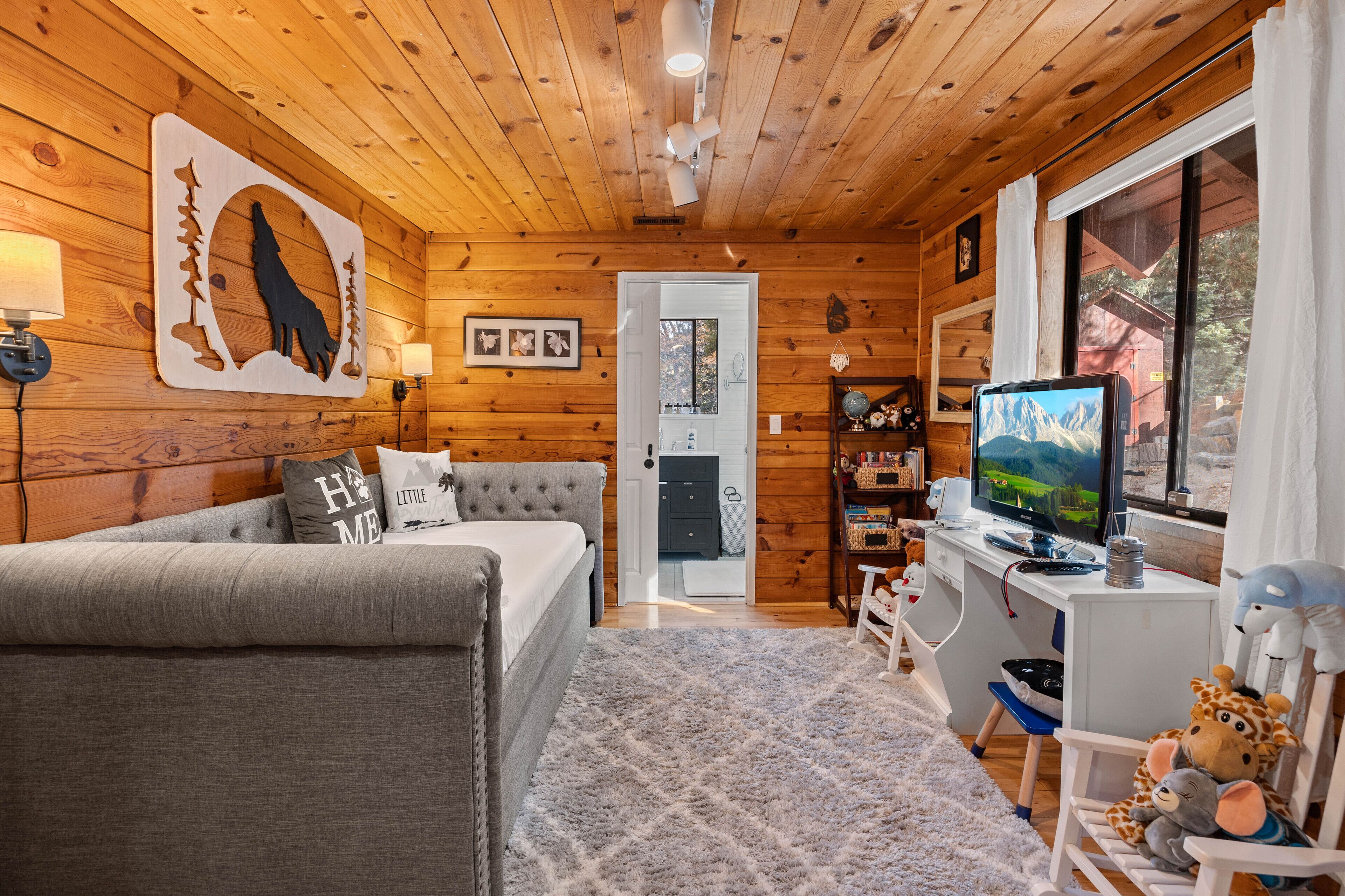 Ein gemütliches Blockhaussinnere mit einer Couch, einem Fernseher und Holzwänden.