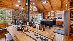 A wooden interior with a dining area, kitchen, and stone wall. - Spacious, Modern Mountain Cabin with Hot Tub (Running Springs)