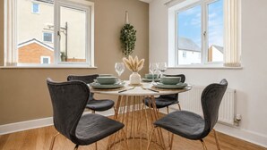 A dining area with a round table, six chairs, and a view of neighboring buildings.