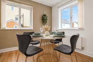 A dining area with a round table, six chairs, and a view of neighboring buildings.