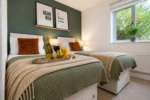 A hotel room with two beds, a breakfast tray with fruits and drinks, and framed wall art.
