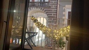 A balcony with a wrought iron railing, a view of a building with a brick facade and arched windows, and decorative lights. - Appartamento nel Centro Storico di Sorrento, Nuovo, con Vista (Sorrento)
