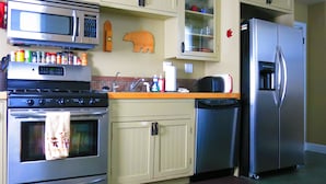 A kitchen with a stainless steel oven, microwave, refrigerator, and dishwasher. There are cabinets, a sink, and various kitchen items on the countertop.