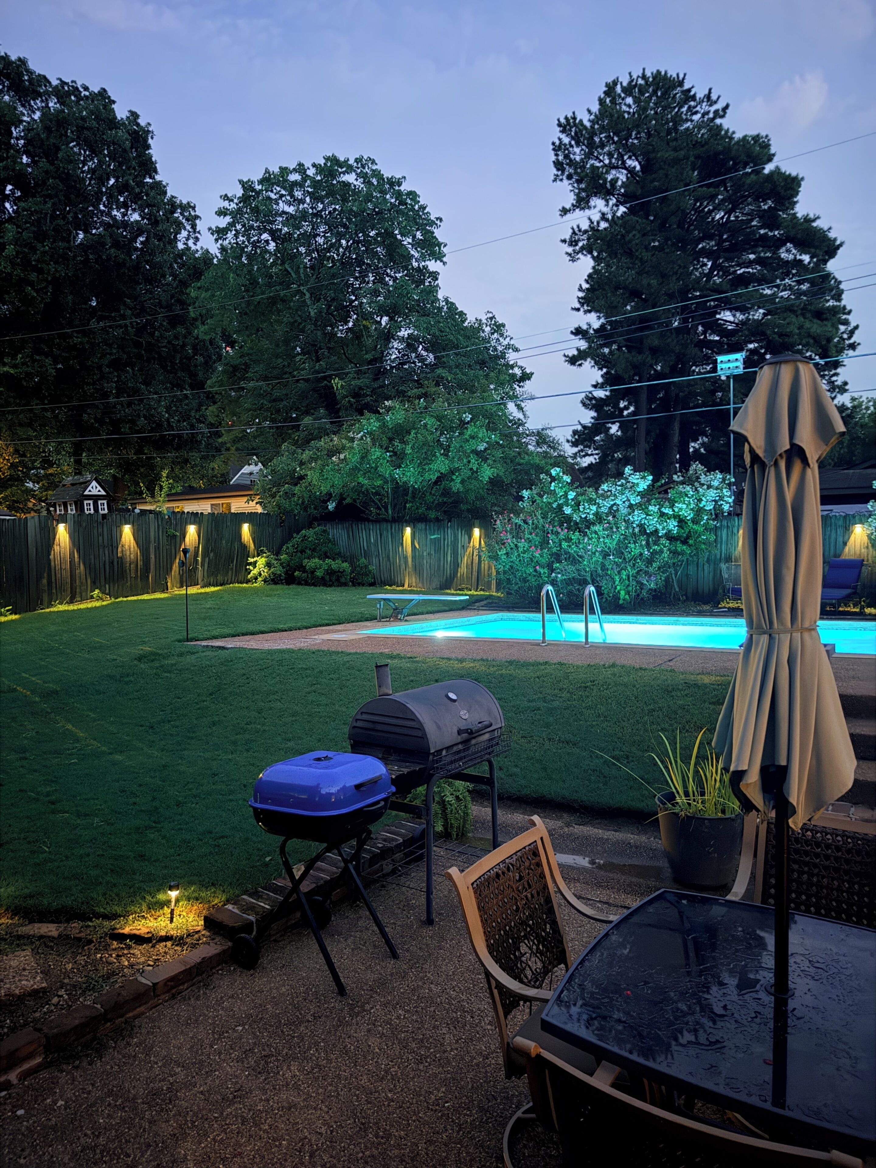 Un giardino sul retro con piscina, barbecue e mobili da esterno.