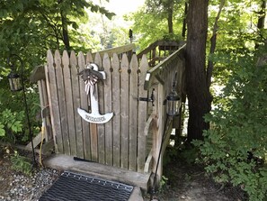 Eine Holzhütte mit einem Schild, auf dem 'WELCOME' steht, und einem daran hängenden Laternen.