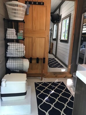 Ein Waschraum mit Holztür, einer weißen Waschmaschine, einem schwarz-weißen Teppich und einem Wäschekorb an der Wand.