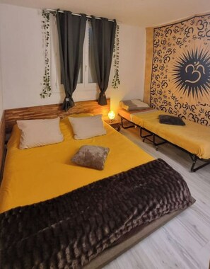 A room with a bed, a bench, and a wall with a sun-like design. - Logement Calme et zen en Provence (Aubagne)