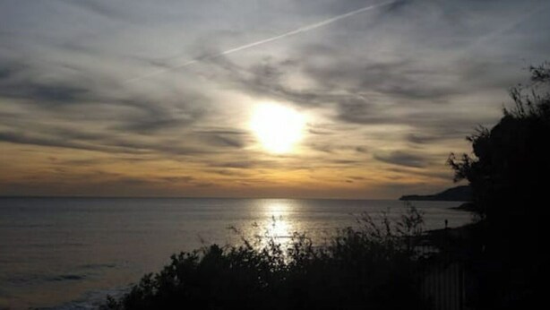 A sunset over a body of water with a clear sky and a distant landmass.