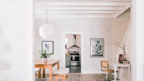 Een moderne keuken met roestvrijstalen apparatuur, een houten eettafel met een bank en een witte hanglamp.