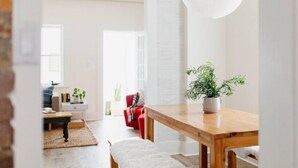 Een moderne woonkamer met een houten eettafel, een witte plant in een pot en een rode bank.