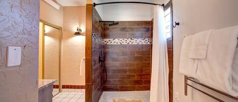 A modern bathroom with a shower, tiled walls, a towel rack, and a visible phone.