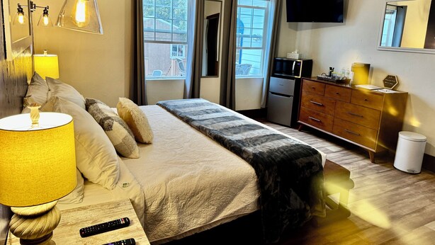 A bedroom with a bed, bedside lamps, a dresser, a television, and a ceiling fan. - Suite102 "The Imperial Eagle" (Custer)