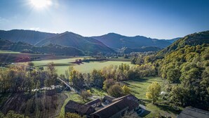 A rural landscape with rolling hills, a clear sky, and a few buildings.