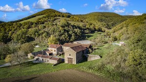 A rural landscape with a stone building surrounded by green fields and hills.