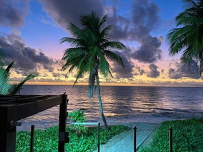 A beach view with palm trees and a wooden deck. - Pé na areia do Caribessa - Branco Haus (João Pessoa)
