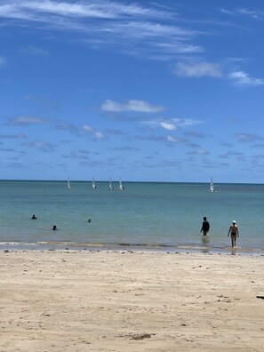A beach with clear skies, calm water, and several sailboats. - Pé na areia do Caribessa - Branco Haus (João Pessoa)