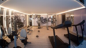 Academia moderna com equipamentos de cardio, estações de musculação e um espelho grande.