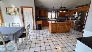 Una cocina con piso de baldosas, armarios de madera, una isla central y un refrigerador.