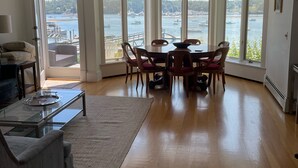 A spacious living room with a large bay window overlooking a harbor. - Historic Oceanfront Home with private dock and boat house. Walkable to town. (Southwest Harbor)
