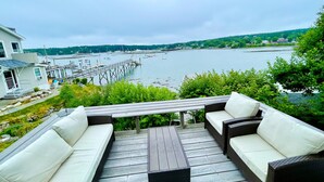A deck with outdoor furniture overlooking a marina and a river. - Historic Oceanfront Home with private dock and boat house. Walkable to town. (Southwest Harbor)