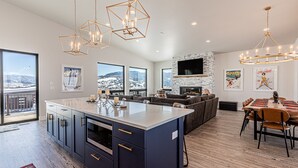 A modern kitchen with a large island, built-in oven, and a dining area with a wooden table and chairs.