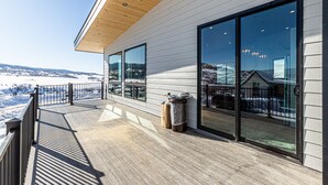A modern building with large windows, a wooden deck, and a view of a snowy landscape.