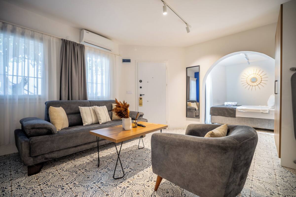 A modern living room with a sofa, armchair, coffee table, and patterned floor.