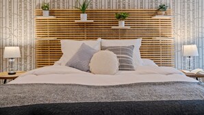 Una cama bien hecha con un cabecero de madera, varios cojines y dos mesitas de noche con lámparas.