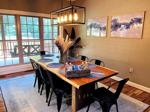 A dining area with a wooden table, black chairs, a hanging light fixture, and artwork on the wall. - Luxury Lodge Fire Pit, Hot Tub, & Sauna (Front Royal)