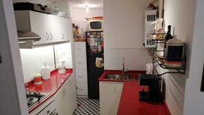 A compact kitchen with a checkered floor, a stove, a sink, and a microwave. - Great location in Barrio Italia, Providencia (Santiago)