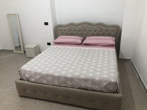 Cama bem arrumada com colcha estampada, cabeceira estofada e dois travesseiros.