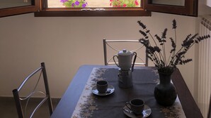 A dining area with a table set for two, a window with a mountain view, and a chair. - Appartamento nel Cuore Della Costa Damalfi (Pietre)