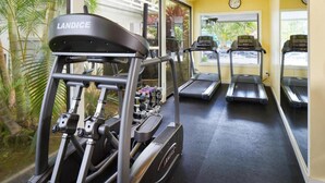Un gimnasio con cintas de correr Landice, una banca de pesas y mancuernas.