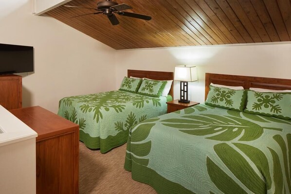 A hotel room with two beds, a ceiling fan, a TV, and a nightstand with a lamp.