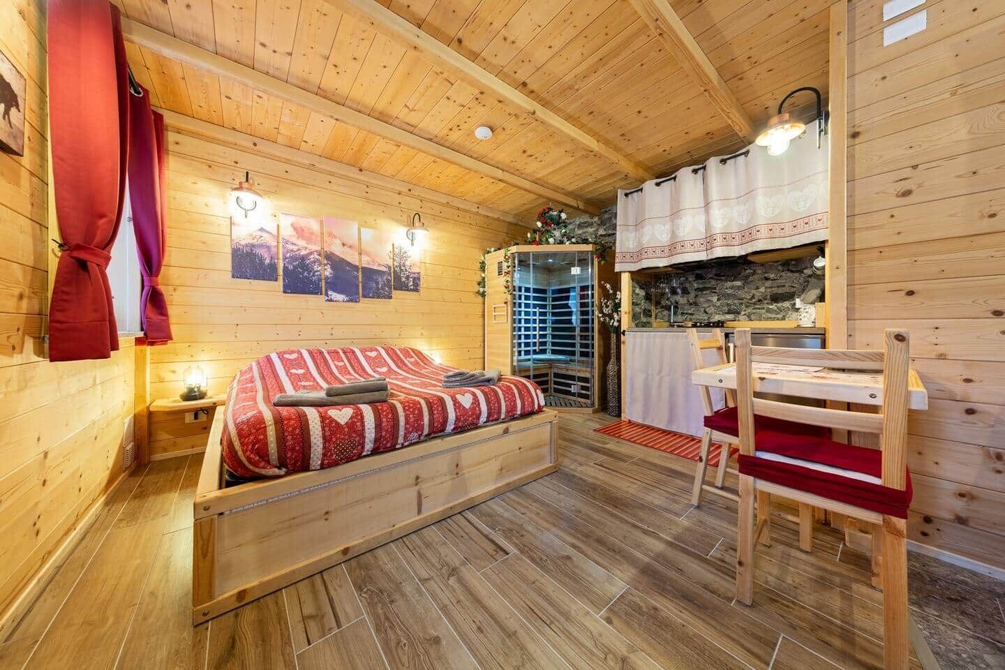 L’intérieur d’un chalet en bois chaleureux et accueillant, avec un lit, une table et un mur en pierre.