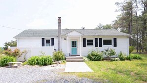 A single-story house with a front porch, a chimney, and a green door. - WATERFRONT!! **HOT TUB**  3 bedroom Oasis on 2+ acres - Sleeps 8 (Cambridge)