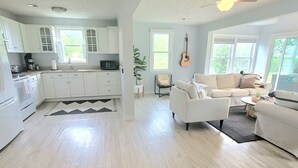 A spacious living area with a white sofa, a dining table, and a kitchen with white cabinets. - WATERFRONT!! **HOT TUB**  3 bedroom Oasis on 2+ acres - Sleeps 8 (Cambridge)