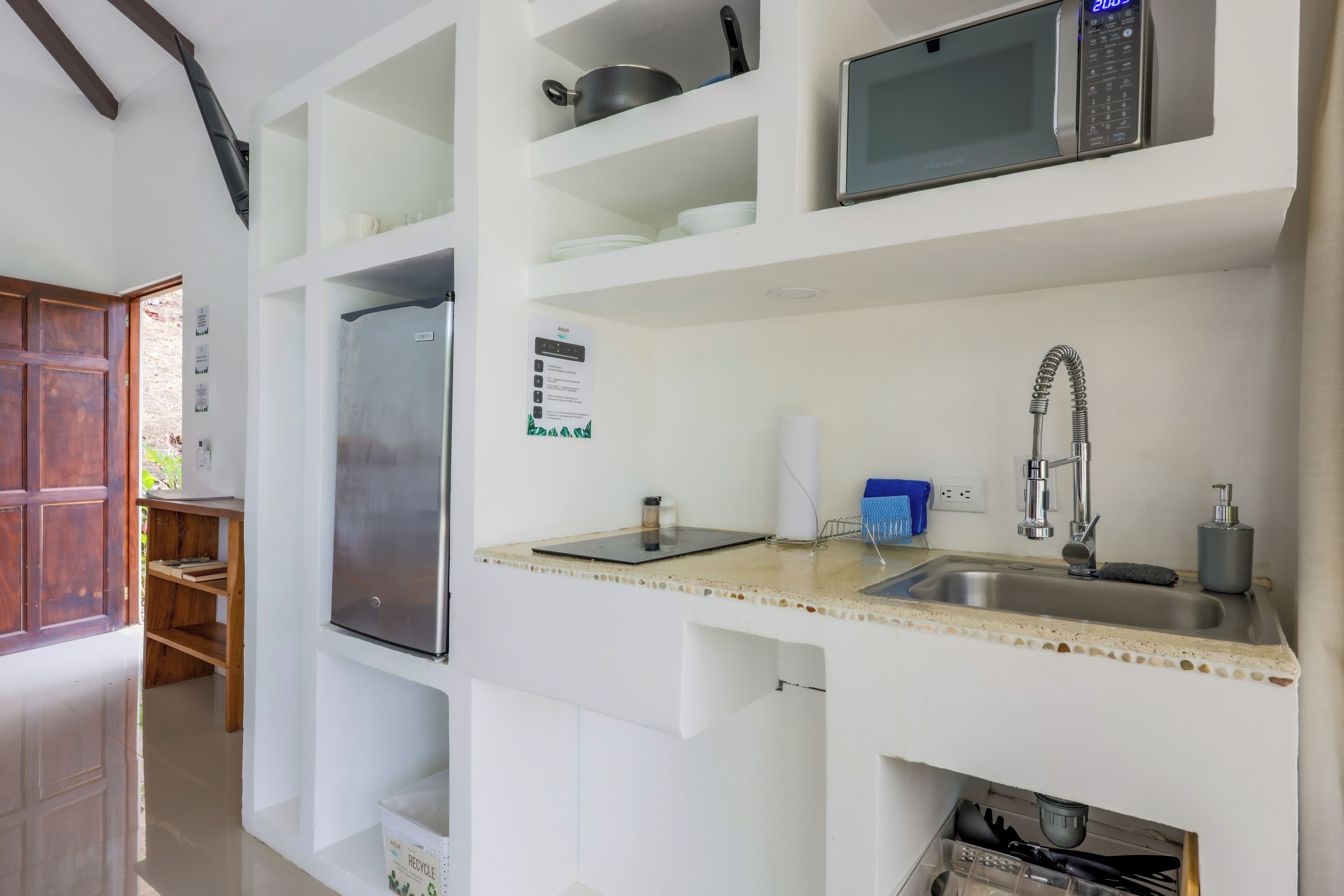 A modern kitchen with a built-in microwave, stainless steel sink, and a refrigerator.