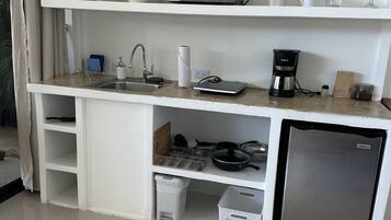 Une petite cuisine équipée d’un four à micro-ondes, d’une machine à café et d’un petit réfrigérateur.