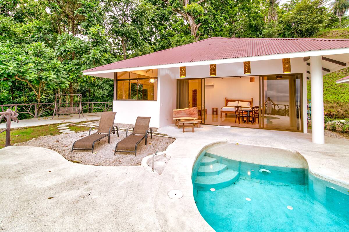 A modern house with a swimming pool, outdoor seating, and a glass door entrance.