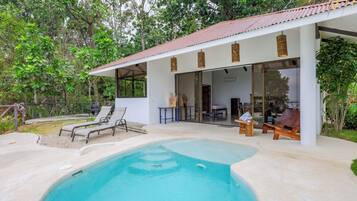 A modern house with a swimming pool, outdoor seating, and a covered patio area.