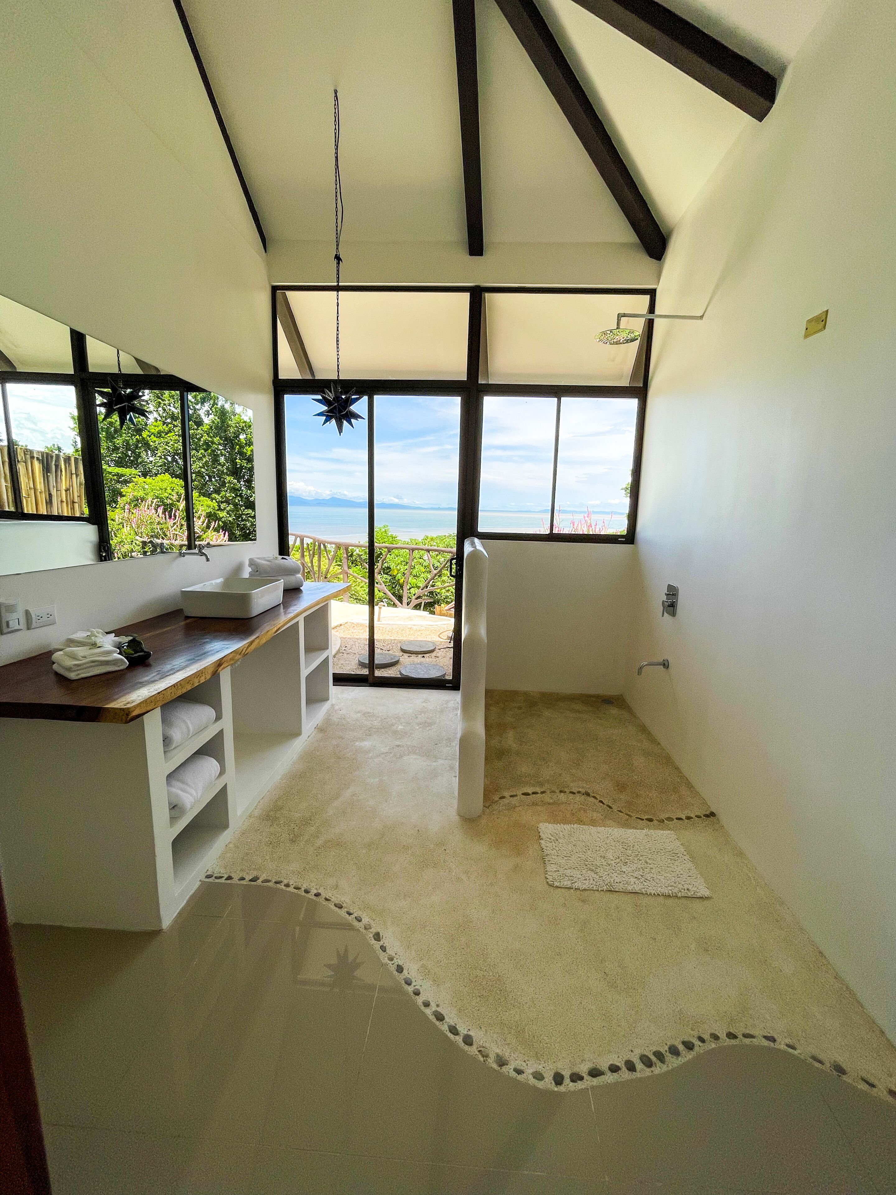 A modern bathroom with a large window, a wooden vanity, and a white sink.