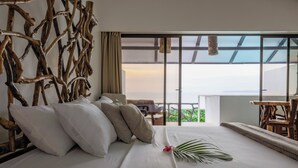 A hotel room with a large bed, a view of the outdoors, and a wooden headboard. - Akua Ocean View Suites (Tárcoles)