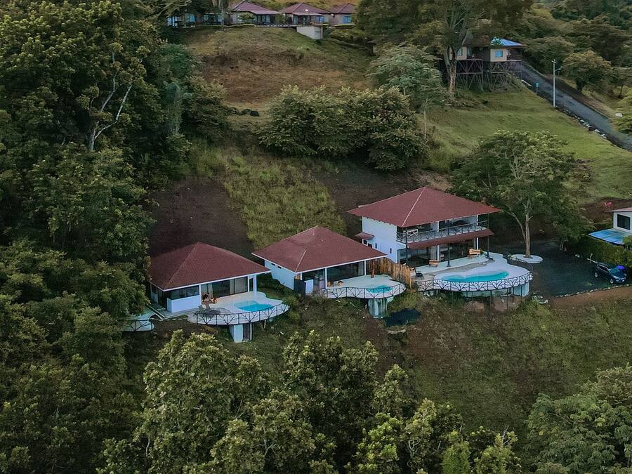 Una propiedad en una ladera con varias casas, una piscina y abundante vegetación.
