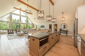 A spacious kitchen with a large island, wooden cabinets, and modern pendant lighting.