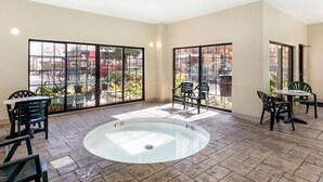 A spacious indoor area with a central pool, large windows, and outdoor views.