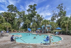 A pool area with lounge chairs and umbrellas, surrounded by palm trees.