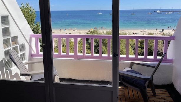 A balcony with a view of a beach and the sea.