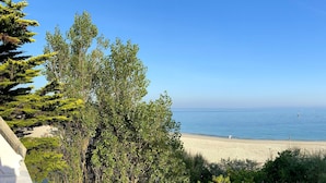 A beach with clear skies, calm water, and a few boats.