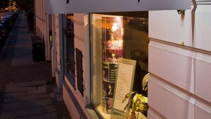 Ein Schild für 'Pension piano forte' mit einer Schaufensterdekoration aus Pflanzen und einer Speisekarte.